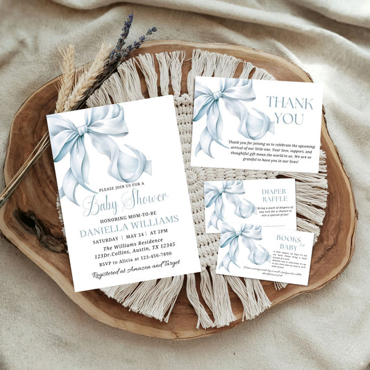 Baby shower invitation set with blue bows on a wooden tray.