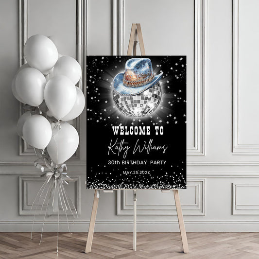 Birthday party sign with disco ball and cowboy hat design, accompanied by balloons on an easel.