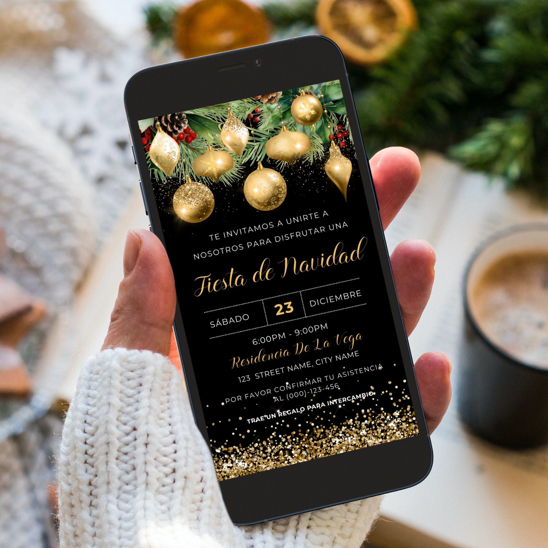 Hand holding a smartphone with a Spanish Christmas invitation on the screen, surrounded by festive decorations.