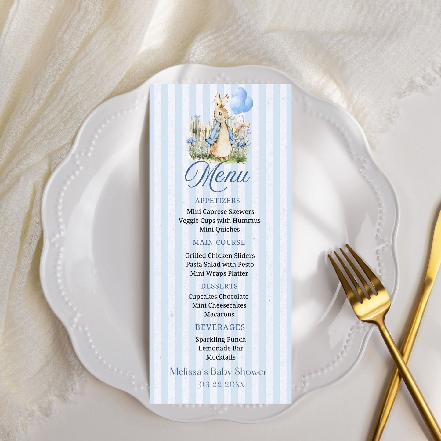 Menu card for a baby shower on a white plate with a gold fork.