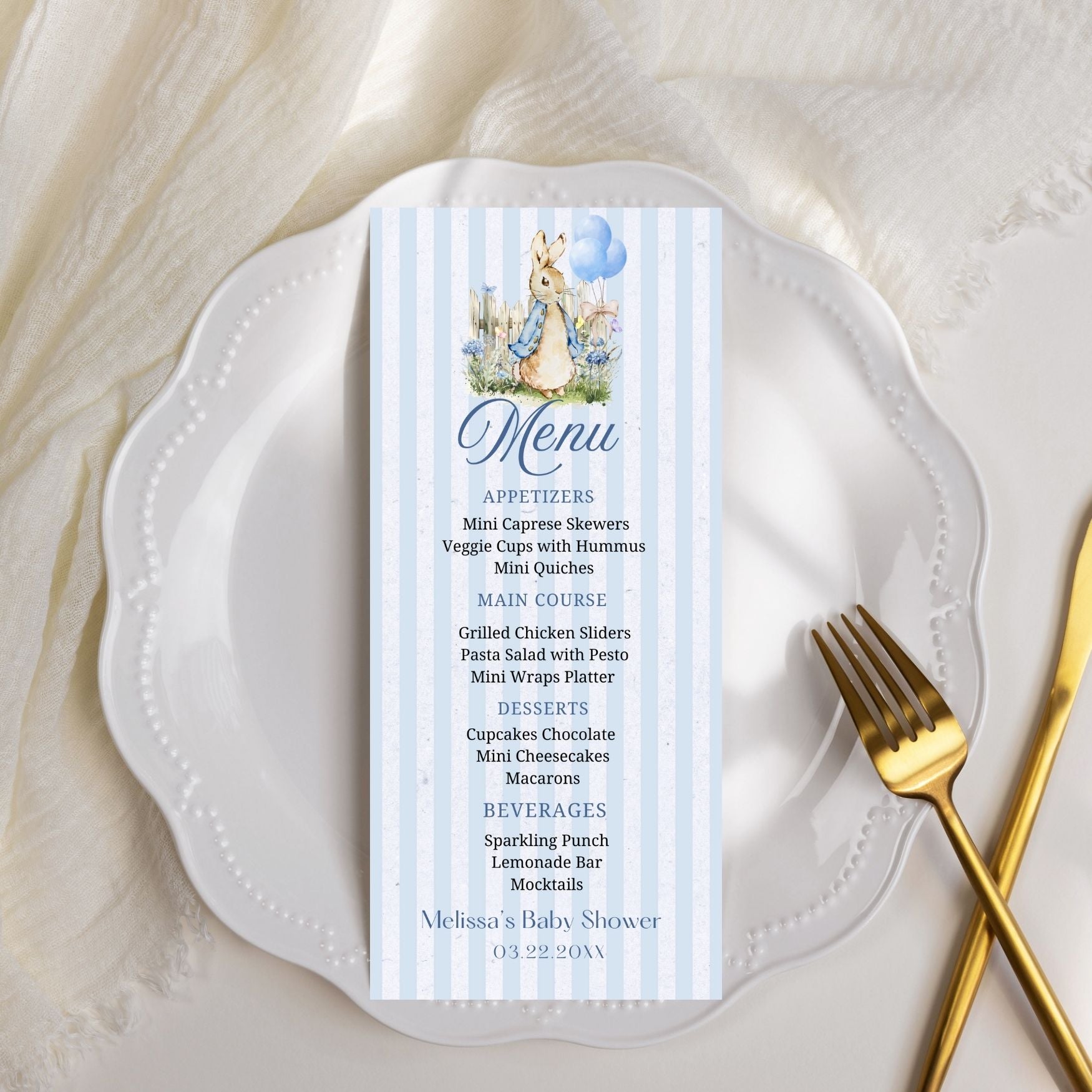 Menu card for a baby shower on a white plate with a gold fork.