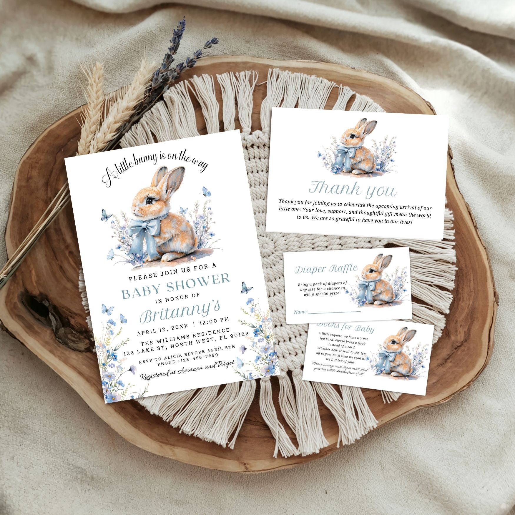 Baby shower invitation set with rabbit illustrations on a wooden tray.