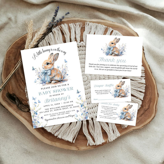 Baby shower invitation set with rabbit illustrations on a wooden tray.