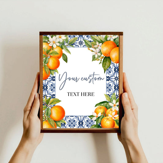 Framed Editable artwork Blue tile  with oranges and flowers held by hands against a plain background