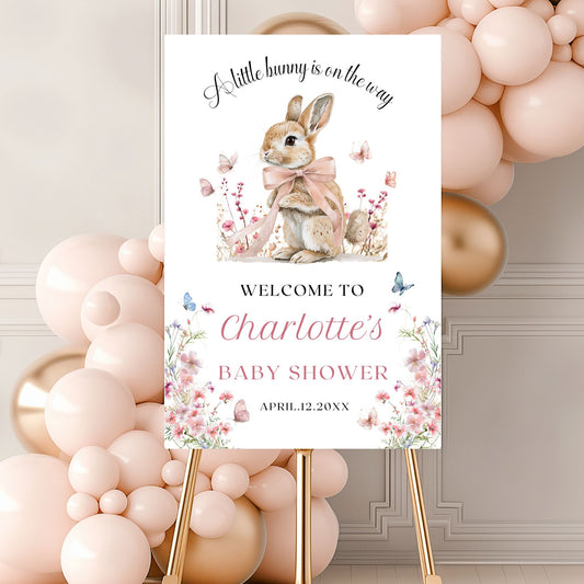 Baby shower sign with a rabbit illustration and wildflowers elements, surrounded by balloons.