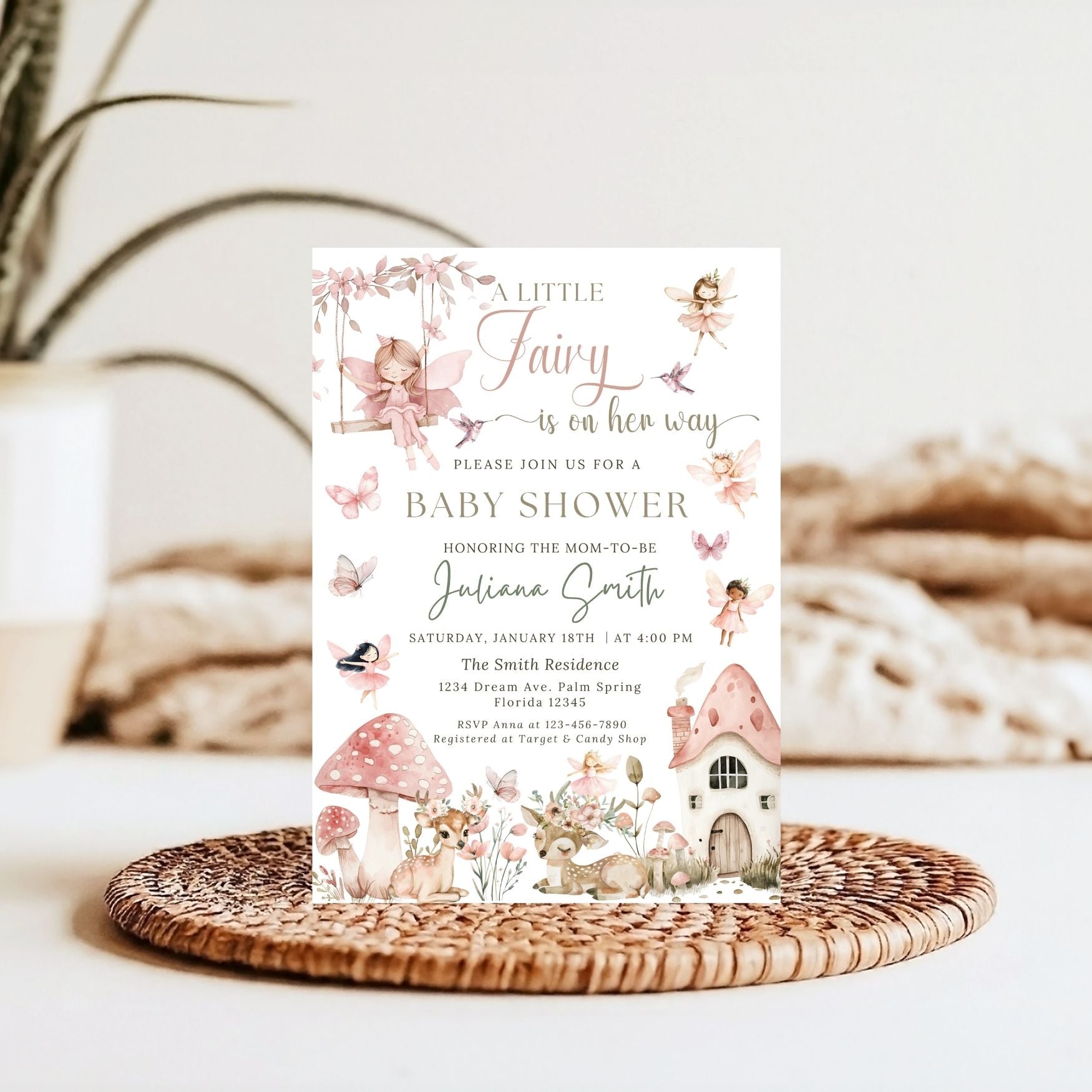 Fairy-themed baby shower invitation on a woven mat with a blurred natural background
