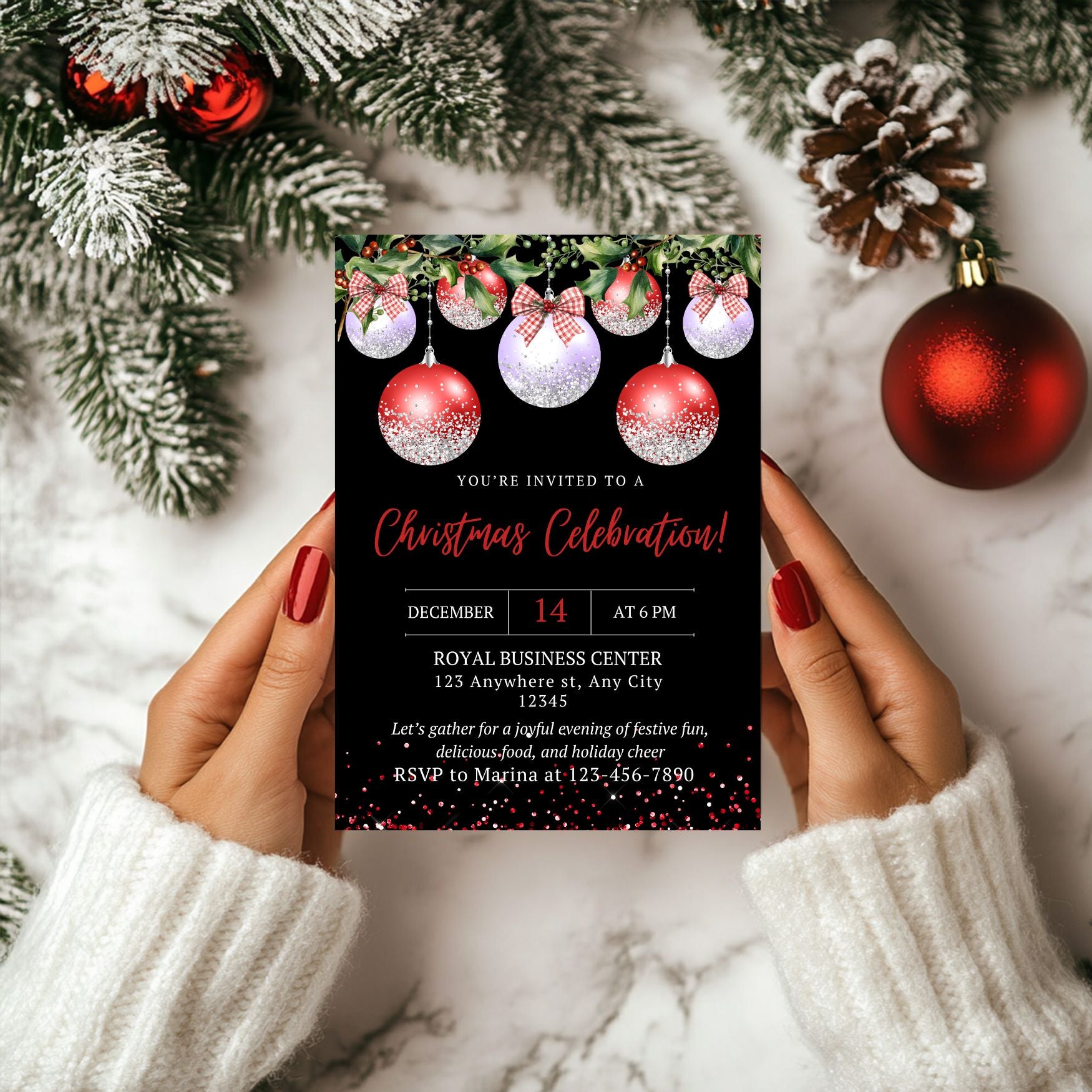 Ornaments Christmas invitation card held by hands with festive decorations in the background